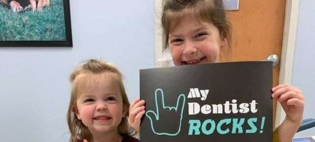 two children smiling and holding sign